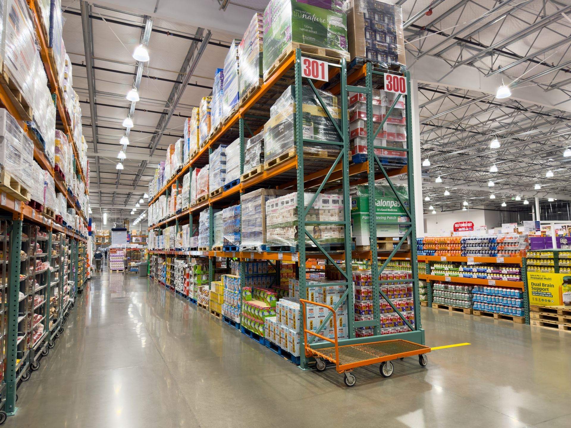 Tall metal shelving units packed with inventory in a brightly lit, spacious warehouse store with a polished floor.