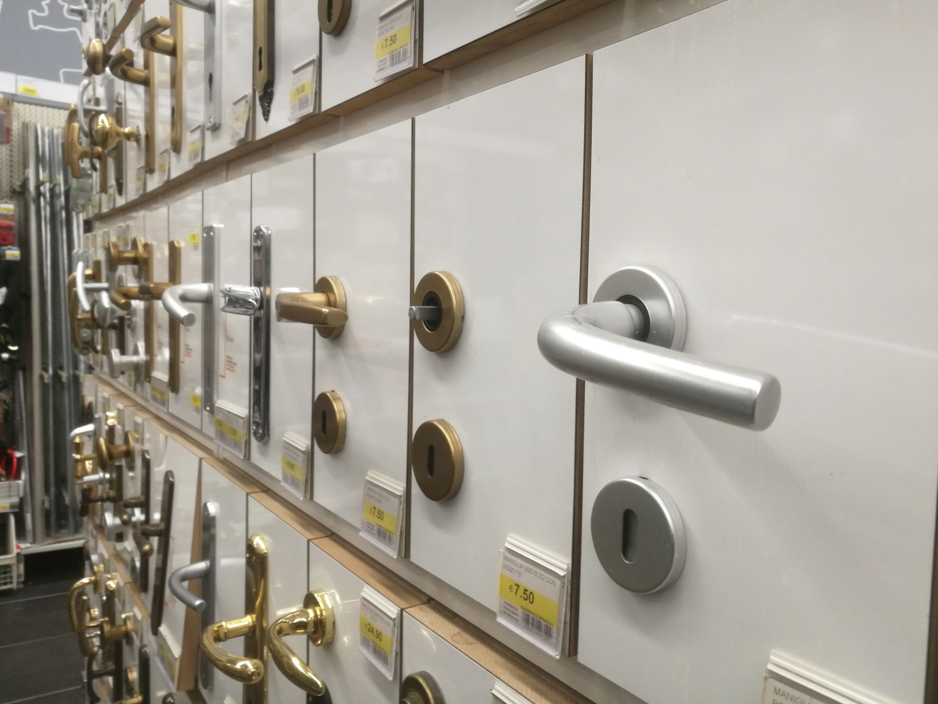 Display wall at a hardware store featuring various silver and gold-toned metal door handles and locks.