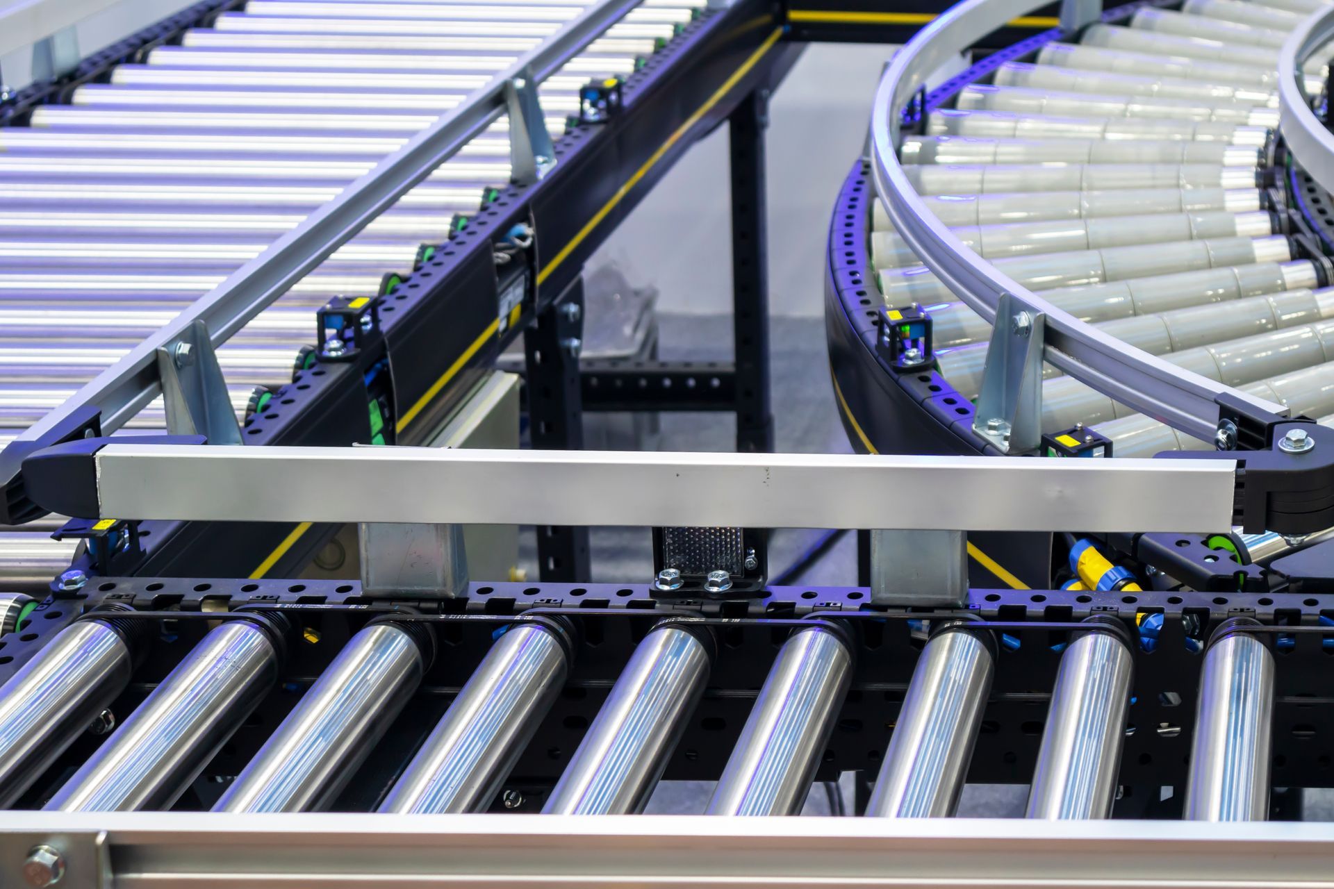 Industrial roller conveyor system with straight and curved tracks for automated material handling.