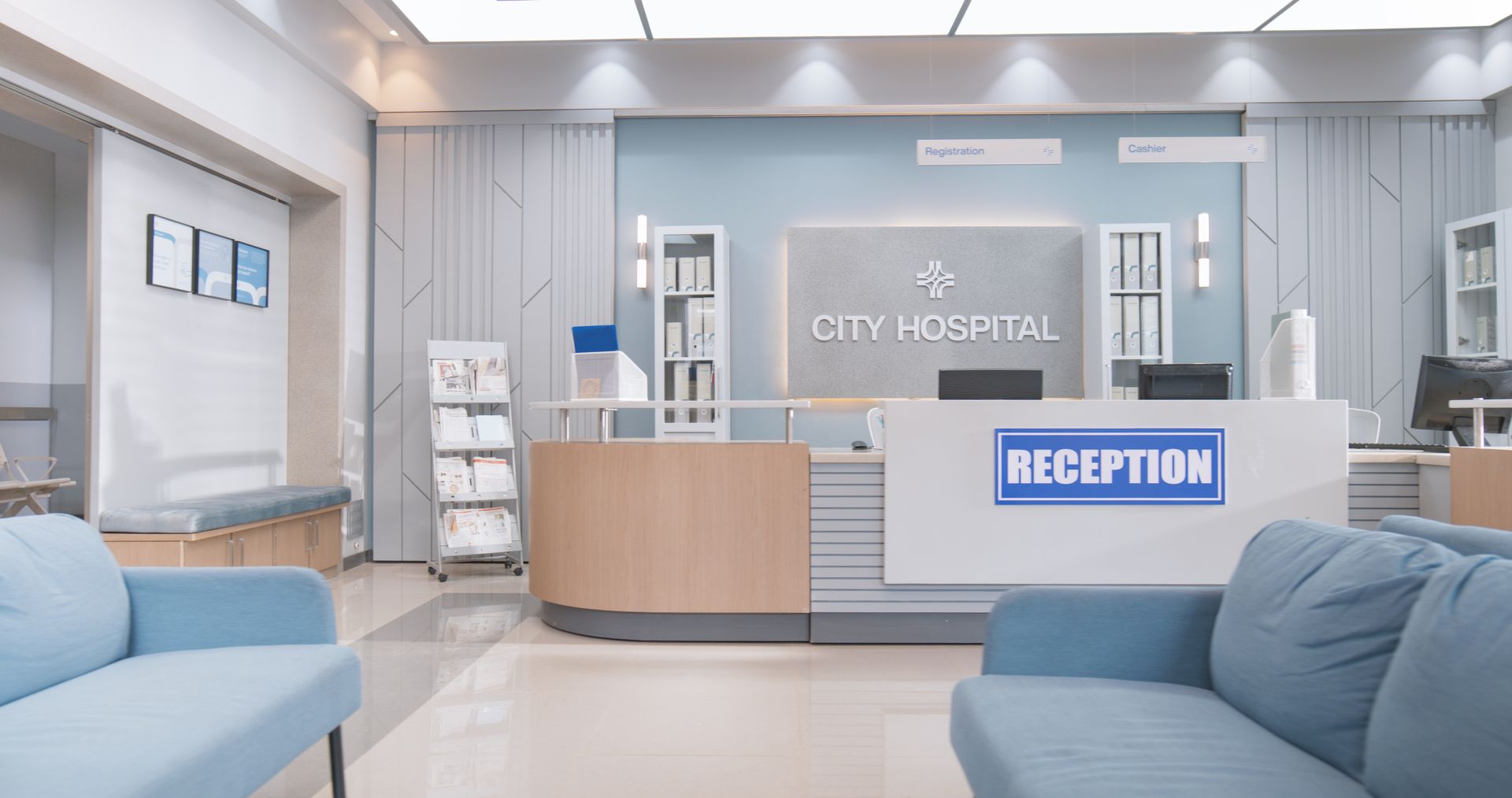 A modern hospital reception area with blue sofas, a light wood counter, and signage reading City Hospital.