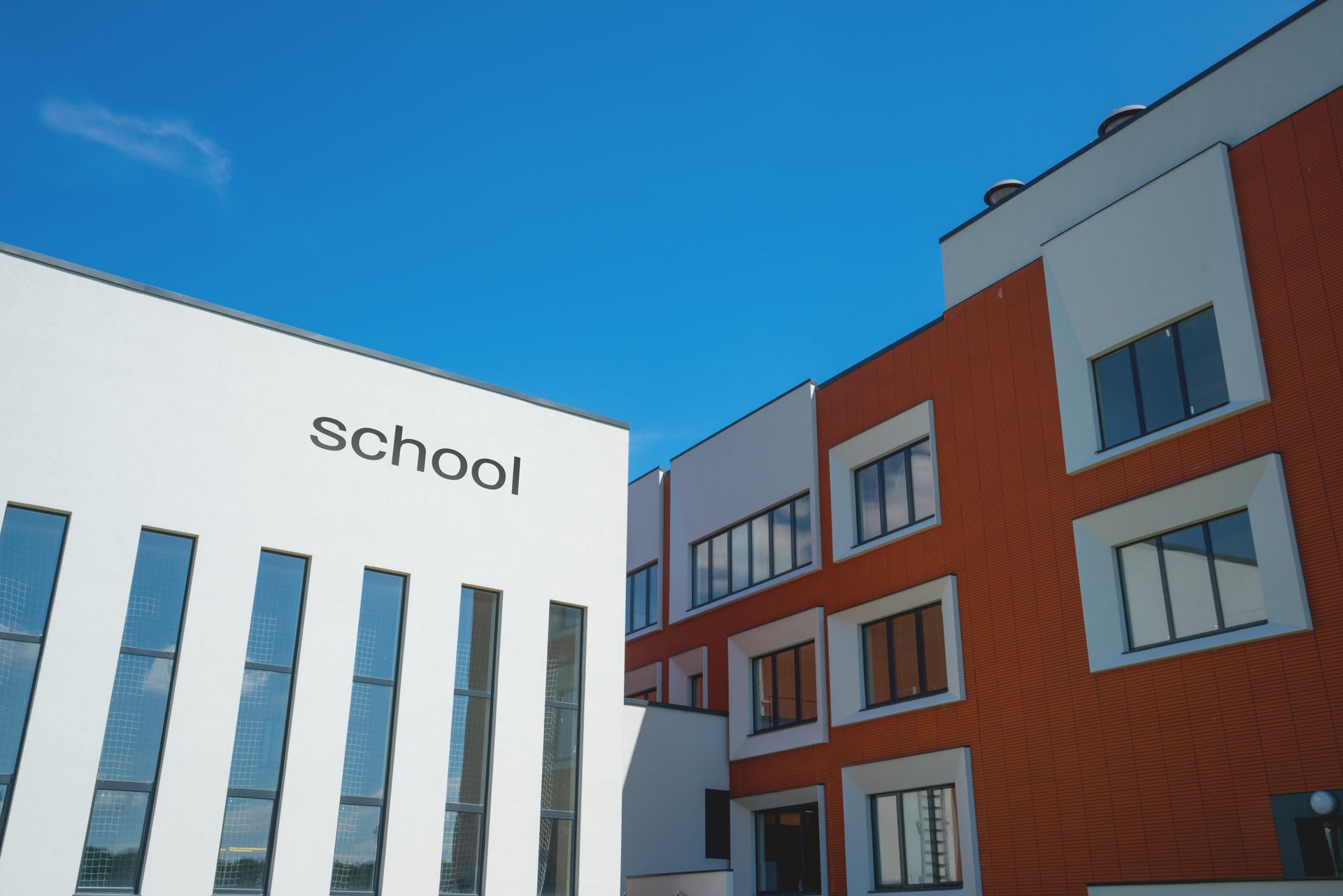 A modern school building with a white facade labeled 