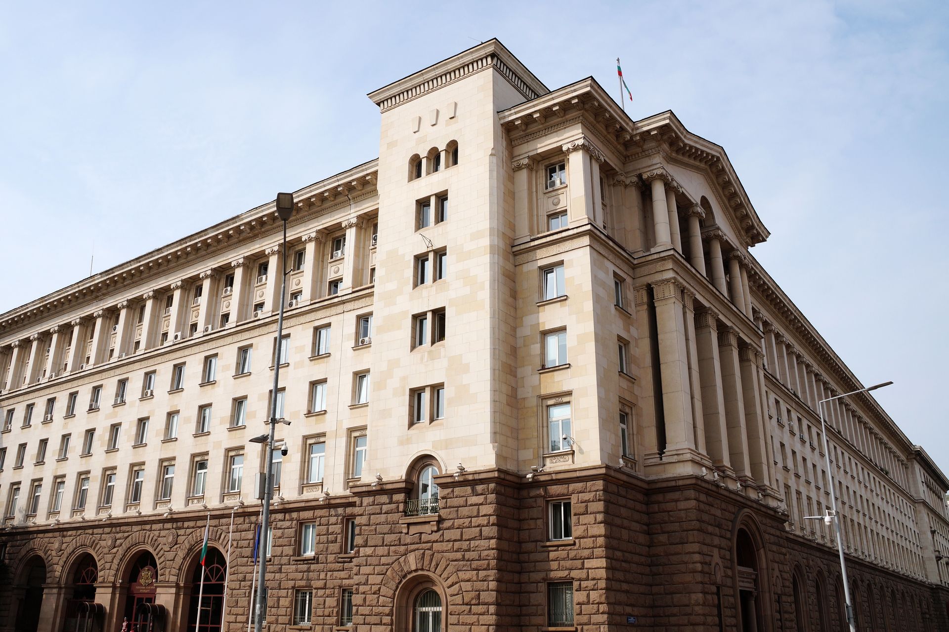 A large, beige, neoclassical government building in Sofia, Bulgaria, featuring a rusticated stone base and tall columns.