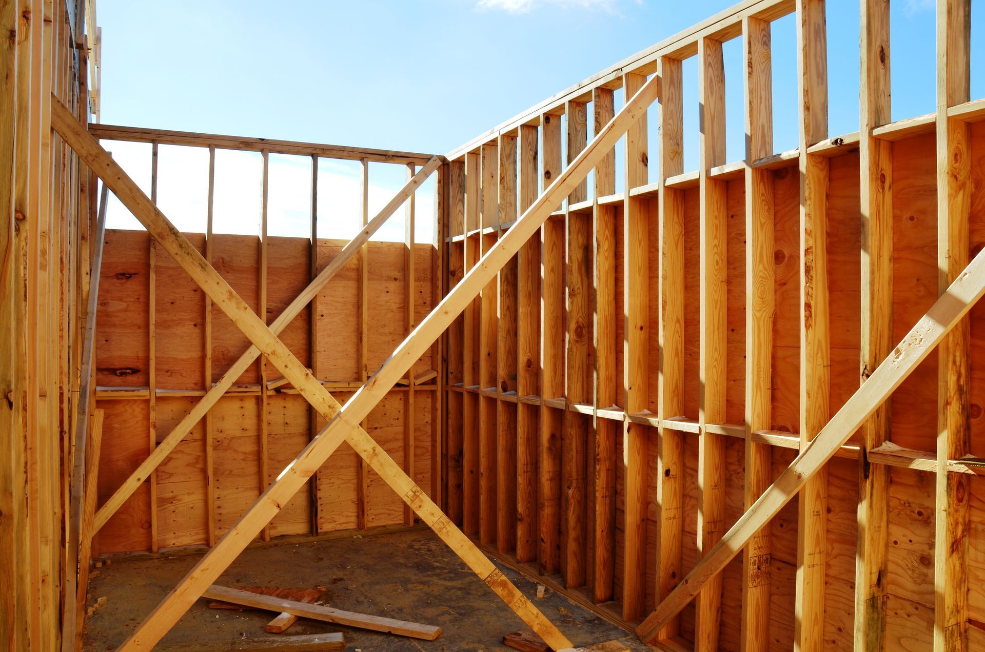 The interior wooden framing of an unfinished building under construction with diagonal temporary bracing.