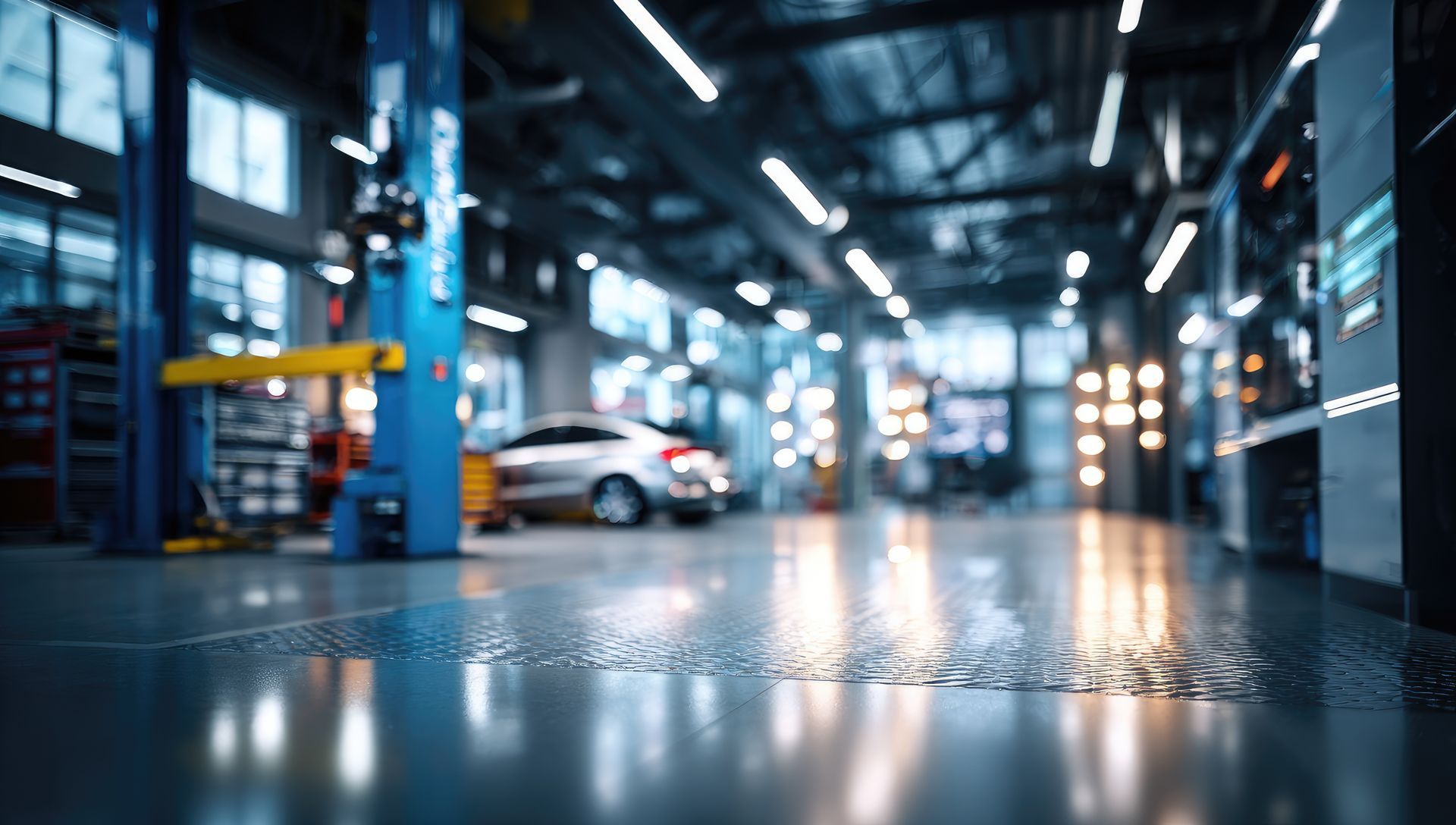 A blurry, low-angle shot of a bright, modern auto repair shop with a car parked in the background.