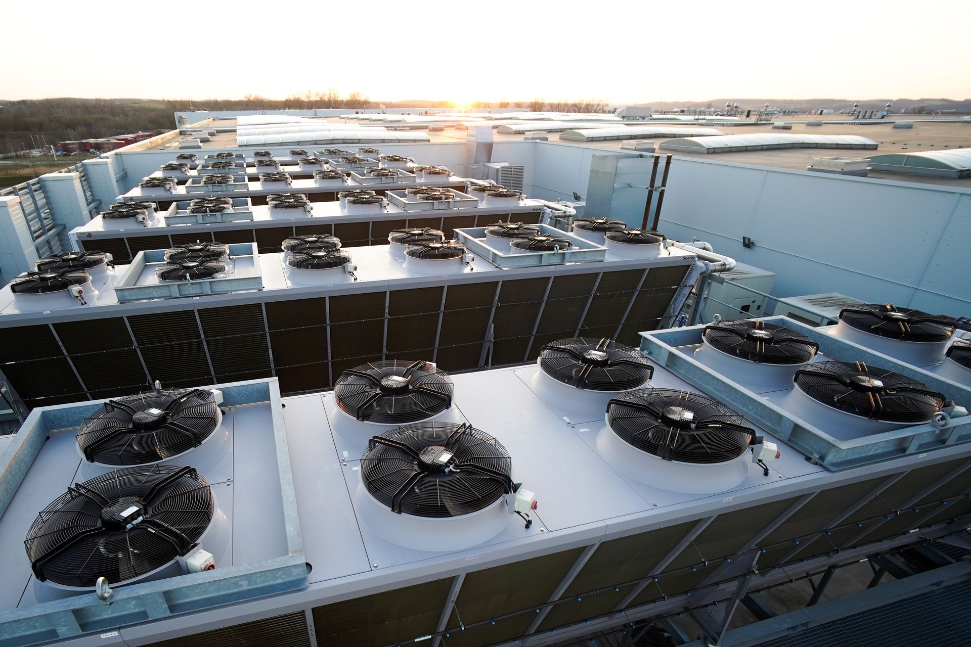 Rows of industrial cooling fans on a large commercial building rooftop.