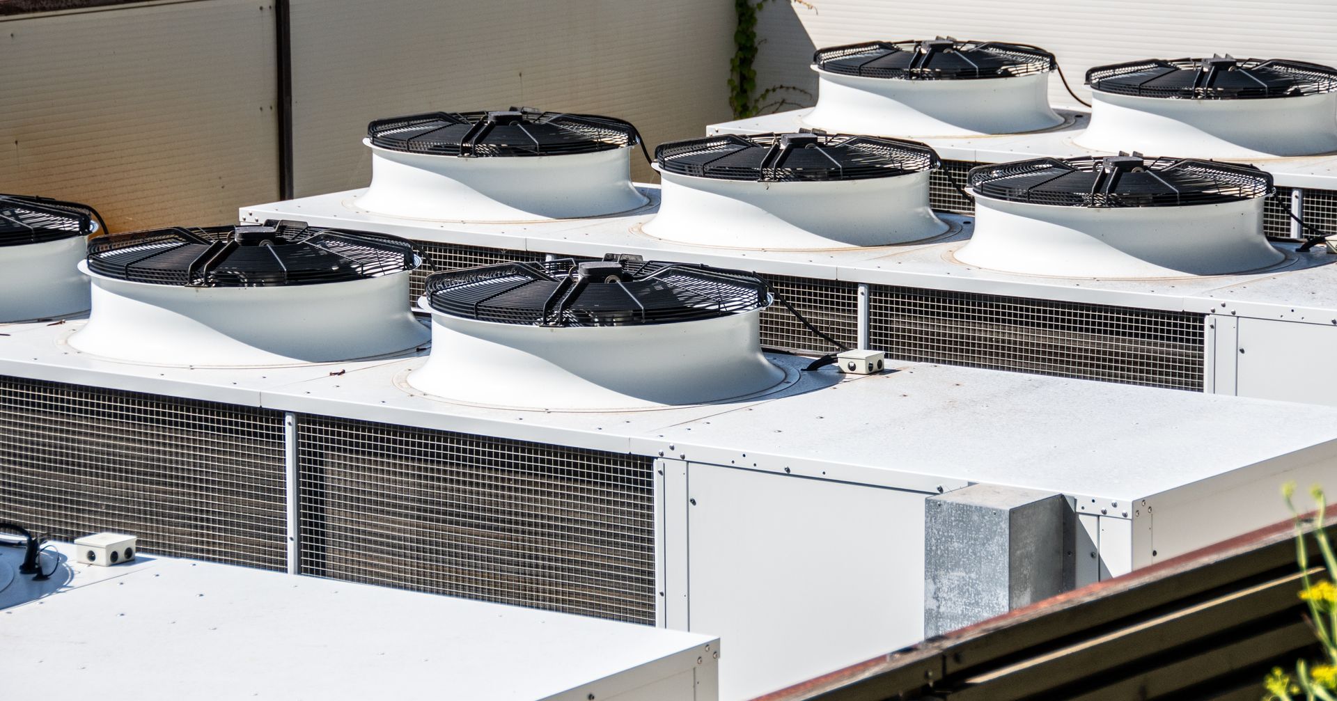 A rooftop arrangement of several industrial HVAC air conditioning units with large, black, circular fan grilles.