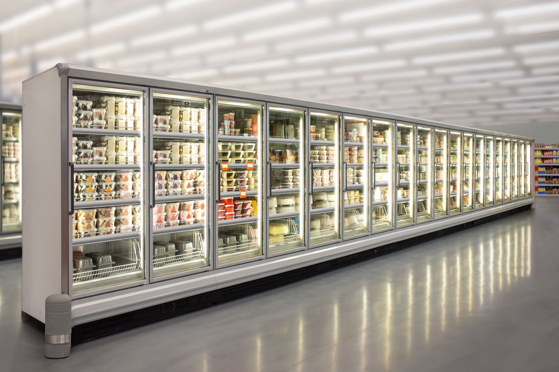 A long row of refrigerated glass-door display cases in a bright, modern grocery store aisle.
