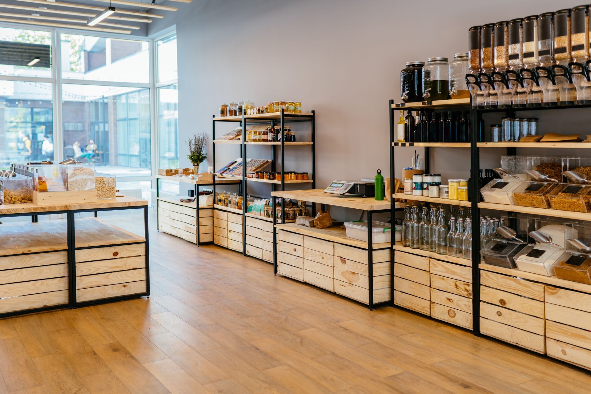 A zero-waste store with wooden crates, shelves stocked with dry goods, and bulk dispenser units.
