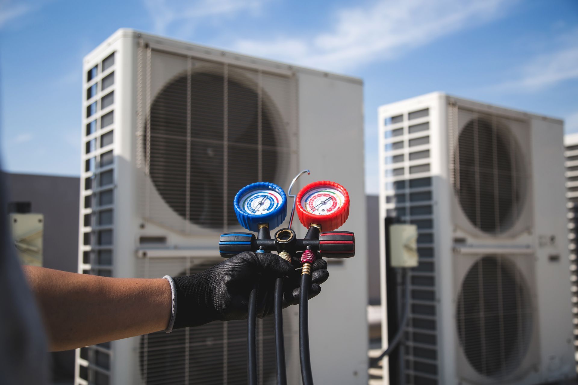 Rows of light-colored HVAC condenser units and industrial piping run along a rooftop against a cloudy sky.