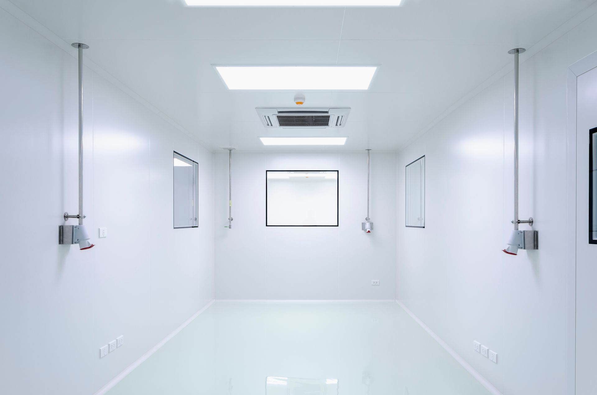 A symmetrical, sterile, white cleanroom with bright overhead lights