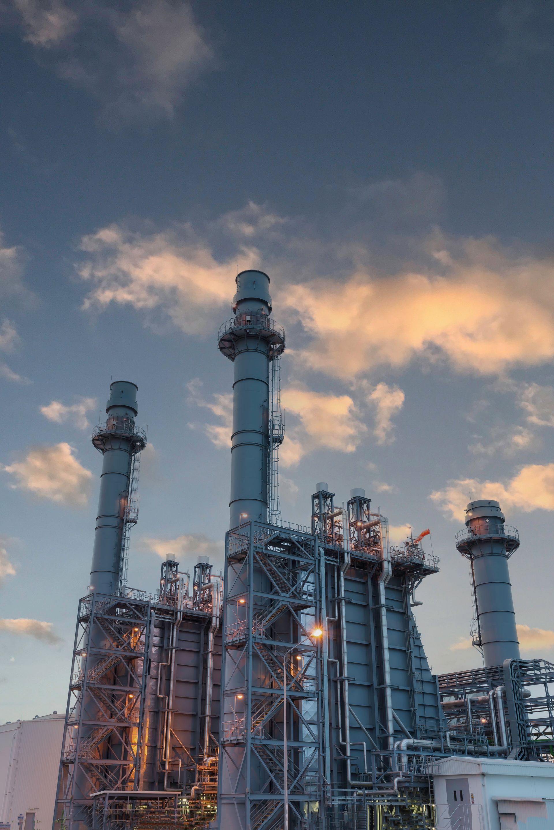 Industrial refinery towers against a cloudy sunset sky