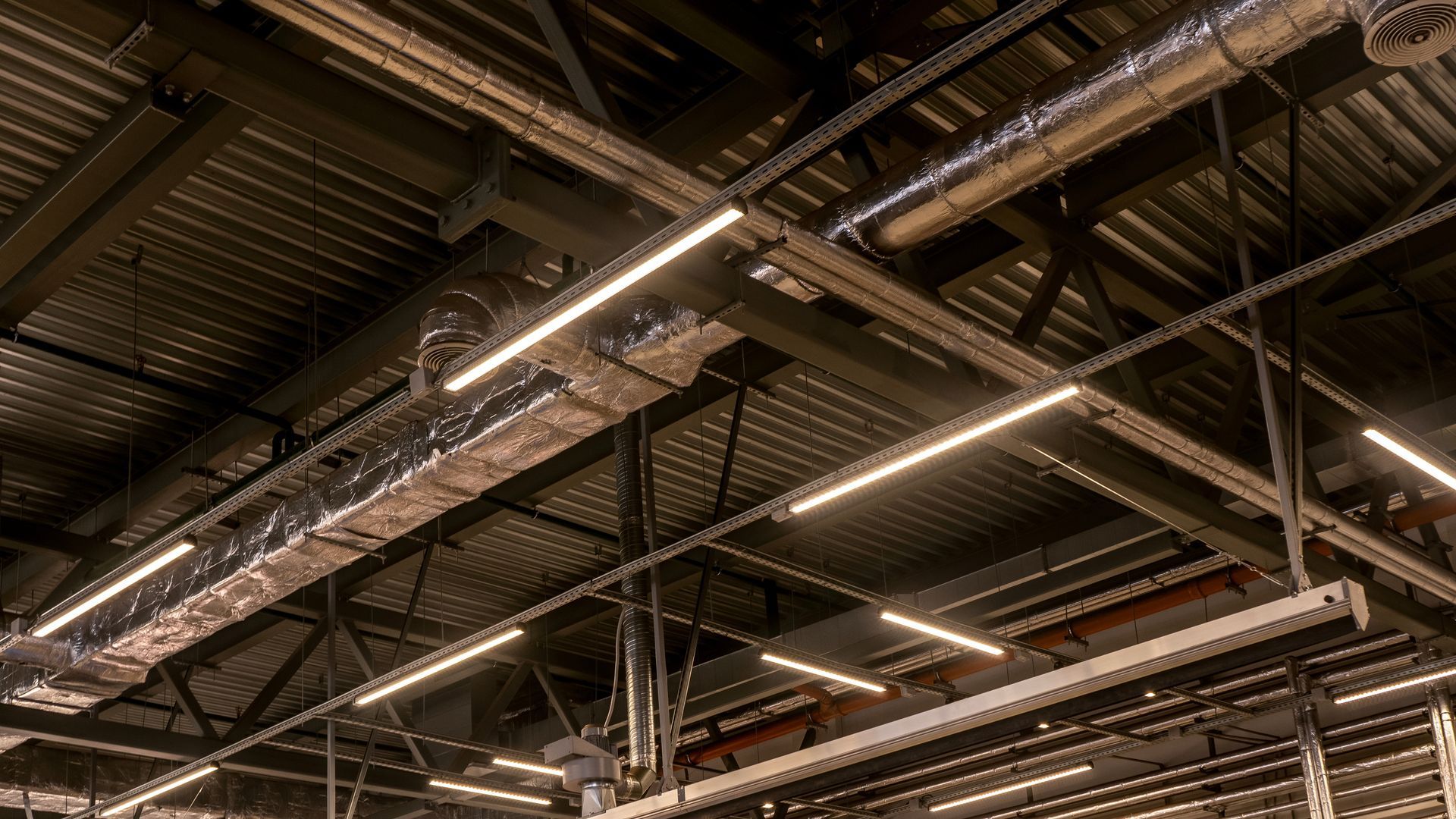 White square air conditioning vent mounted on a ceiling with a section of ductwork visible above it.
