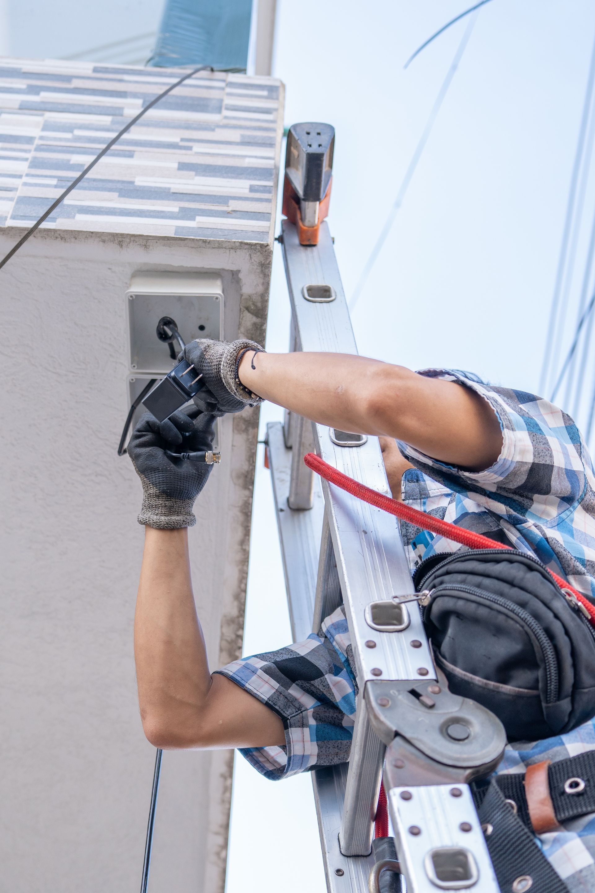 Worker in safety harness drilling into a building ledge while hanging from ropes