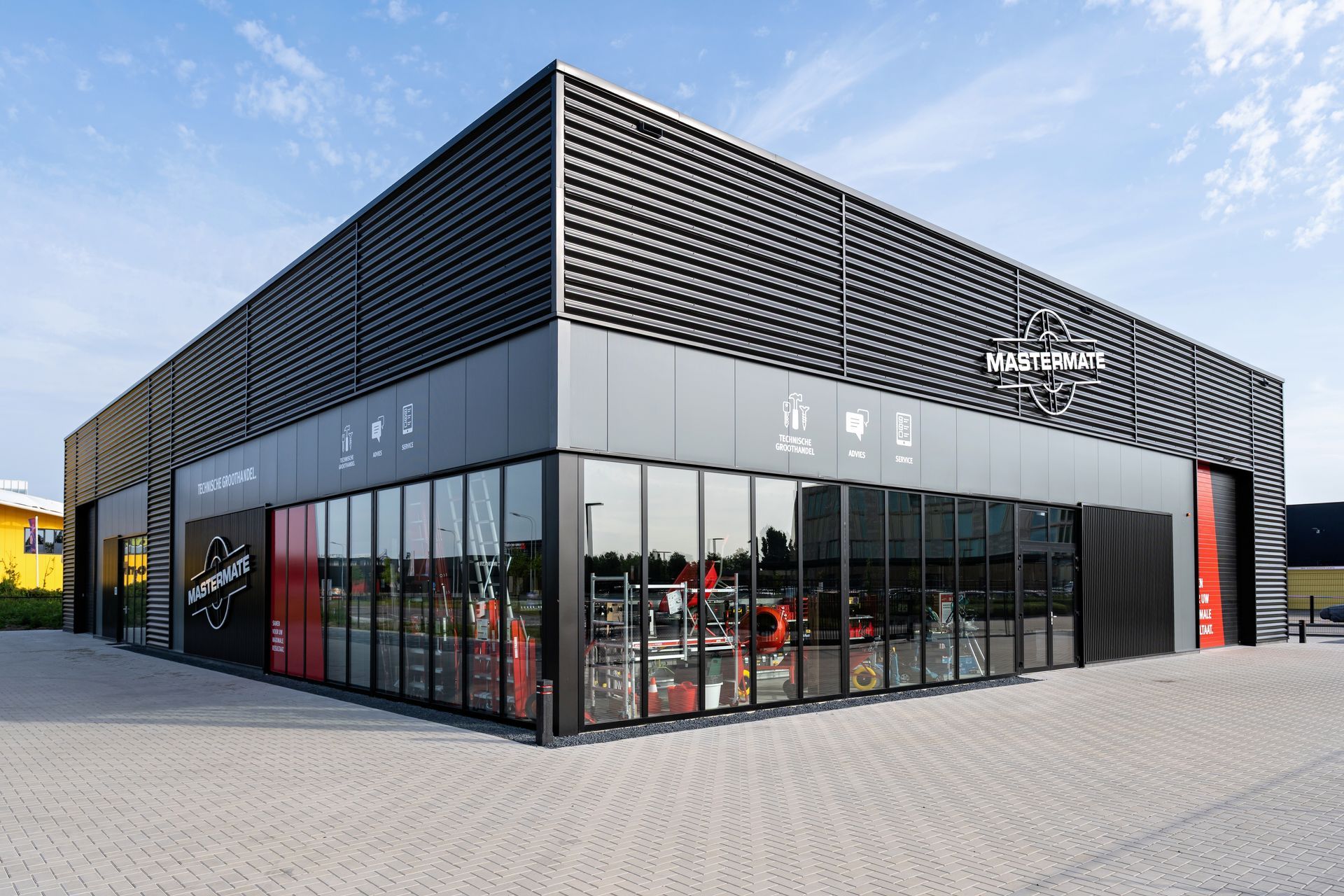 Modern commercial building with large glass windows, a dark metallic facade, and a sign reading 