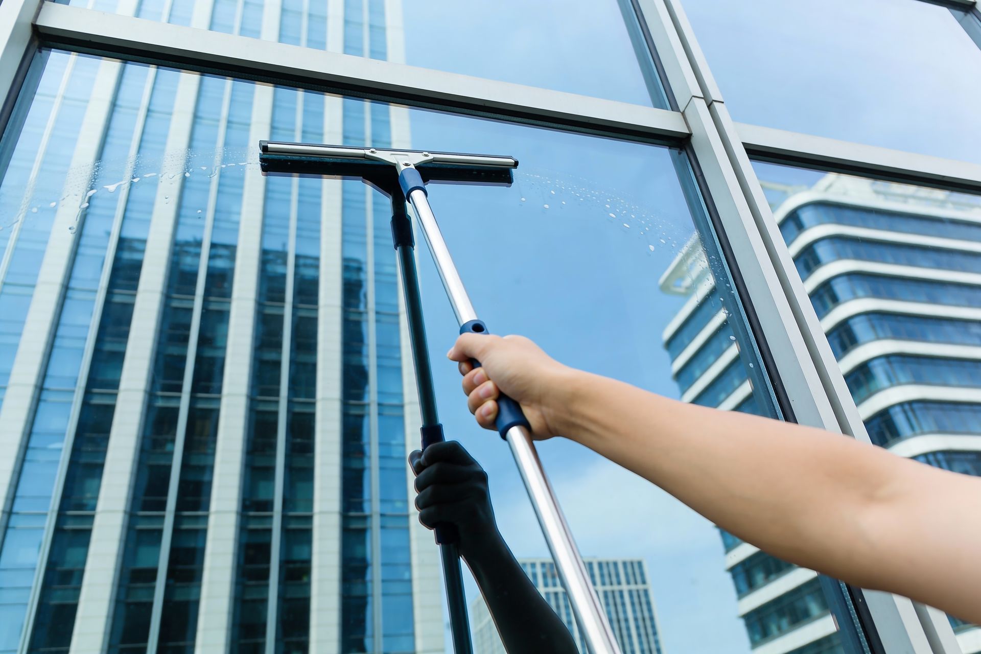 A power washer nozzle sprays water to clean a light-colored stone staircase, revealing a clean strip against dirty stone.