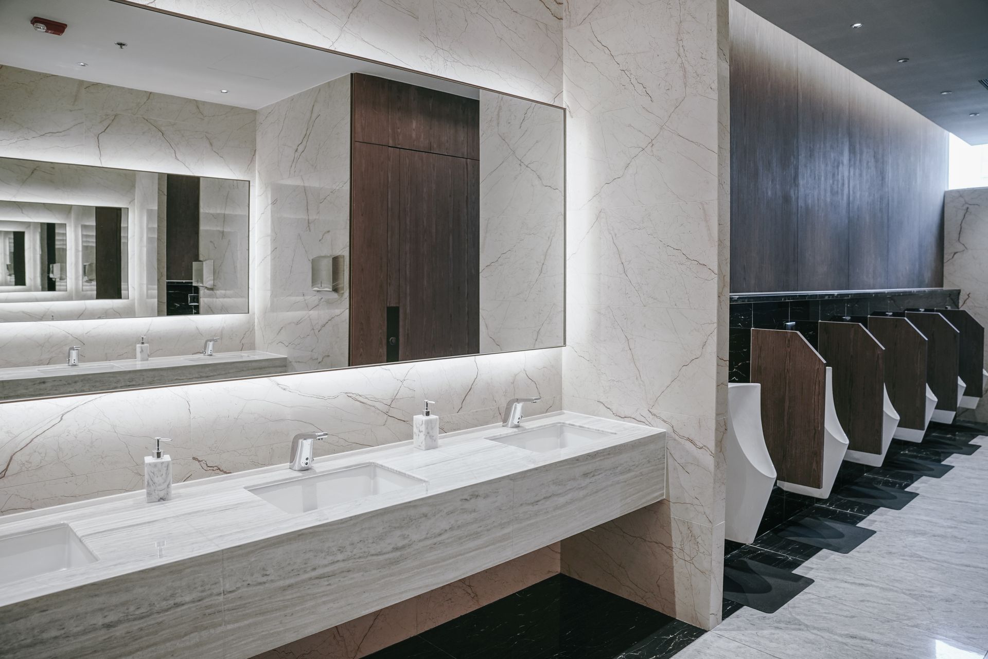 White urinals mounted on a tiled wall in a public restroom.