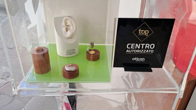 Ufficio con scrivania, sedie, computer e cartelle cliniche alla parete.