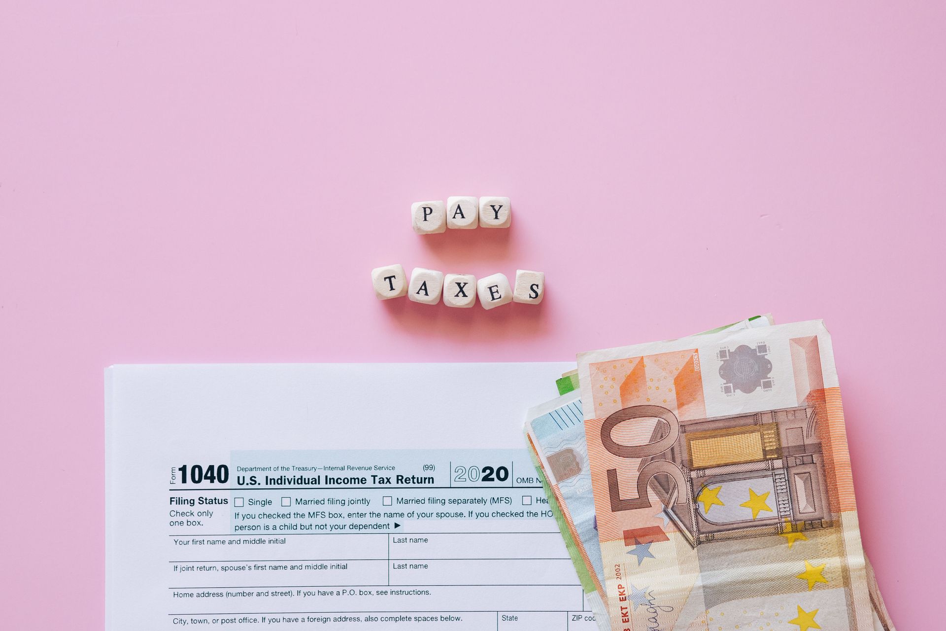 Daisy flowers made from small pills above a check and euro banknotes on a pink background