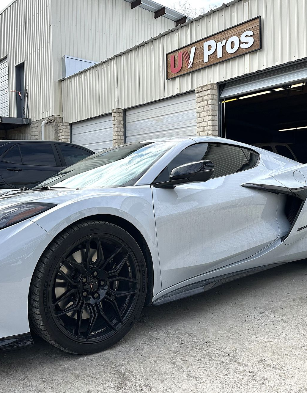 Gray Corvette parked in front of a business,