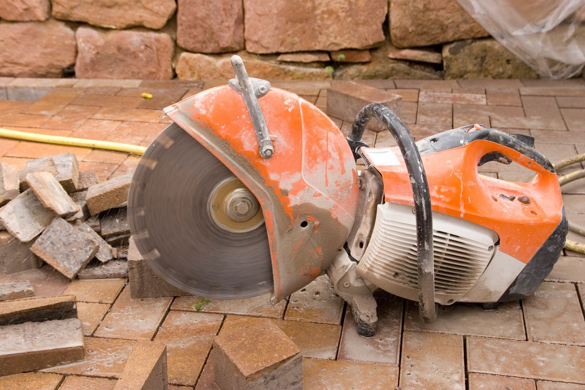 A circular saw is cutting bricks on a brick floor.