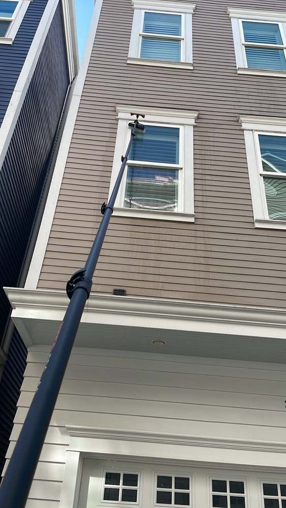 Black pole reaching up to a beige house with white-trimmed windows and gray siding