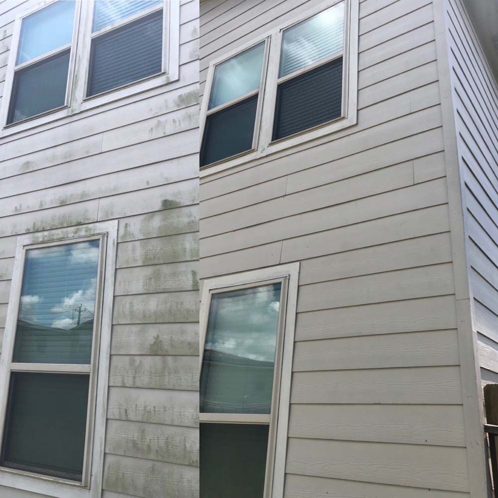 White house siding with several windows and greenish stains near the lower left corner