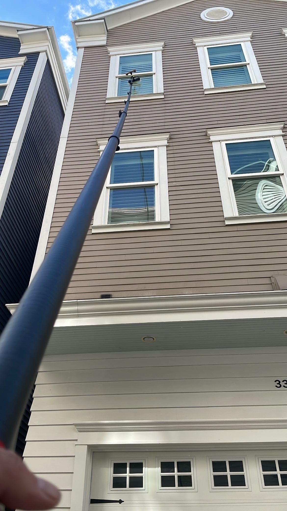 Low-angle view of a patterned apartment building facade with windows and a blue pole in the foreground.
