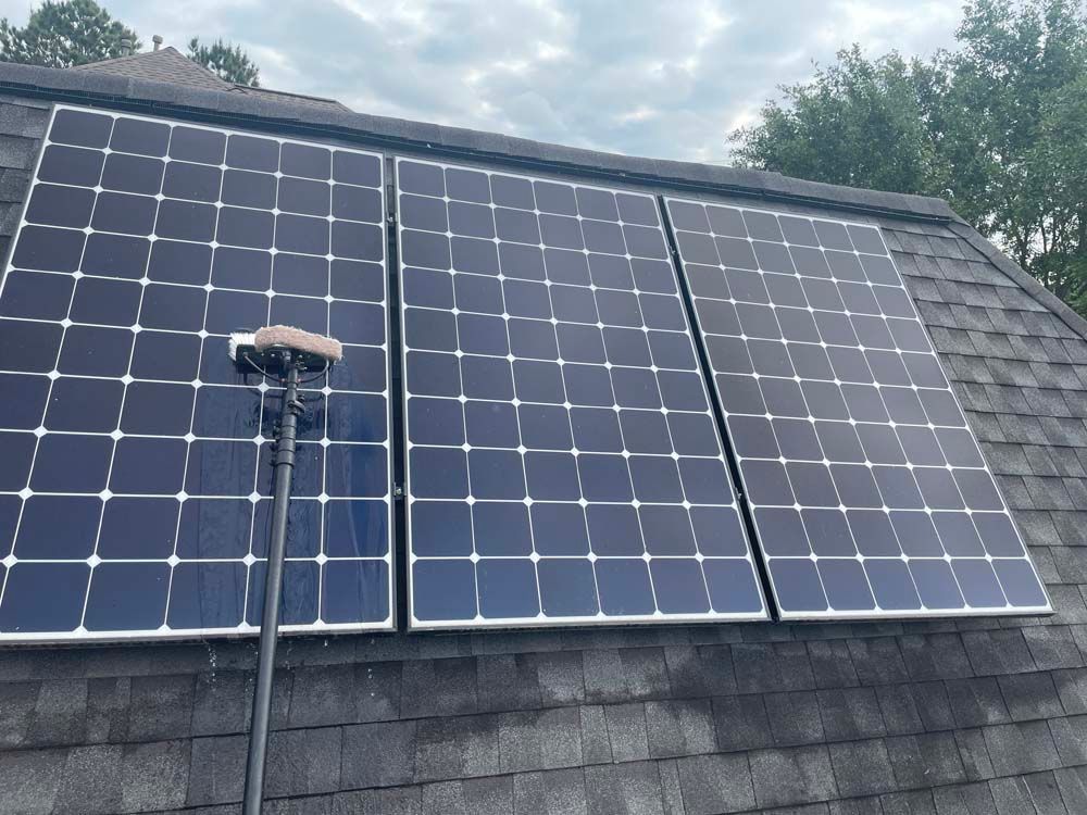 Solar panels mounted on a shingled roof with a cloudy sky above