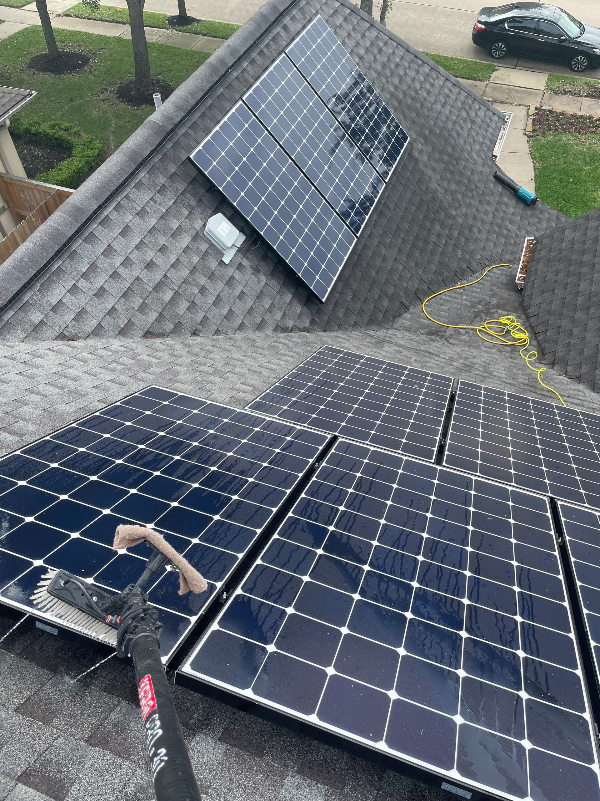 Solar panels on a shingled rooftop, with a worker installing panels near a dormer.