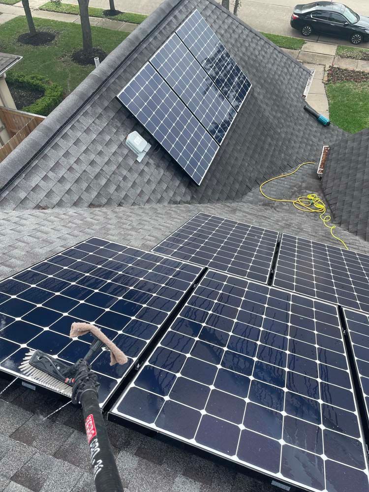 Solar panels installed on a gray shingled roof, with a ground-mounted panel visible below.