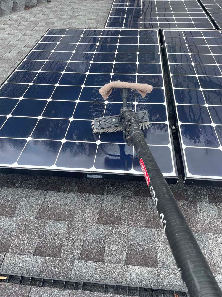 Cleaning solar panels with a brush on a rooftop.