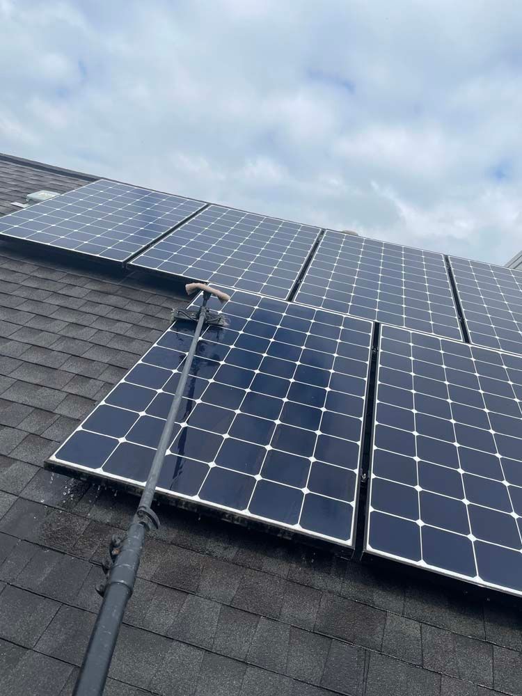 Solar panels mounted on a shingled roof under a cloudy sky, with a conduit running to them