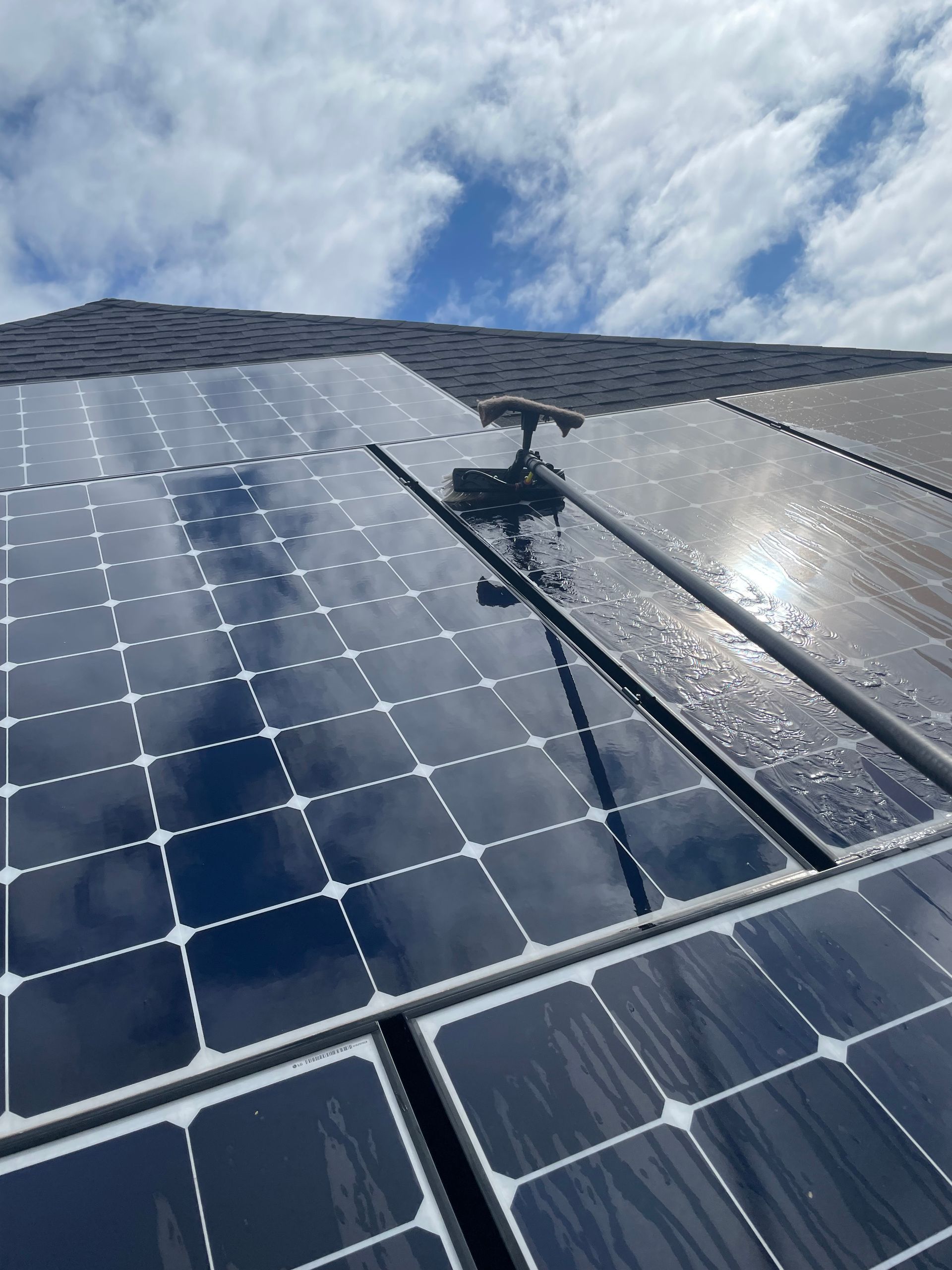 Solar panels reflecting sunlight under a blue cloudy sky.