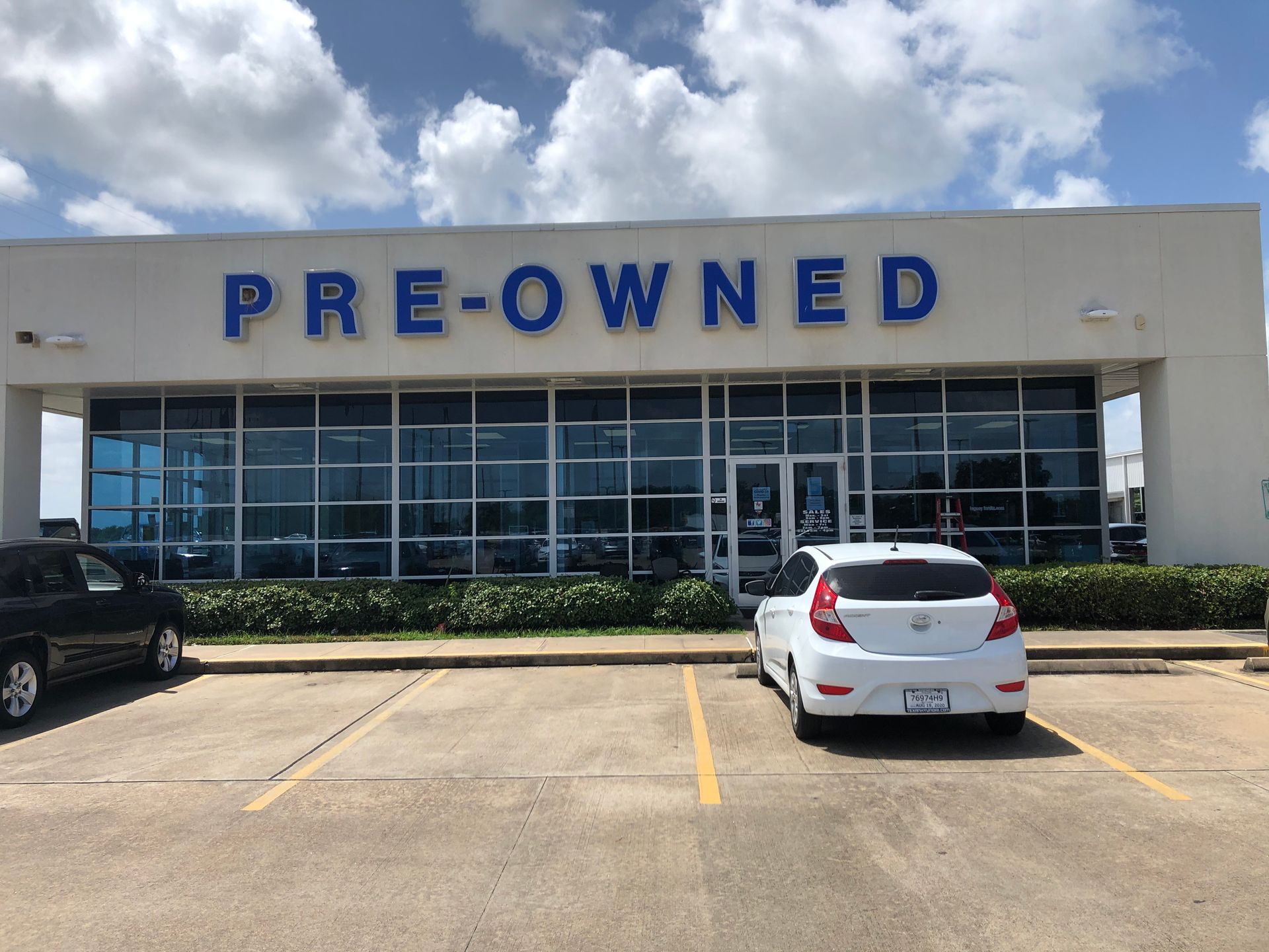Pre-owned car dealership storefront with parked vehicles in front