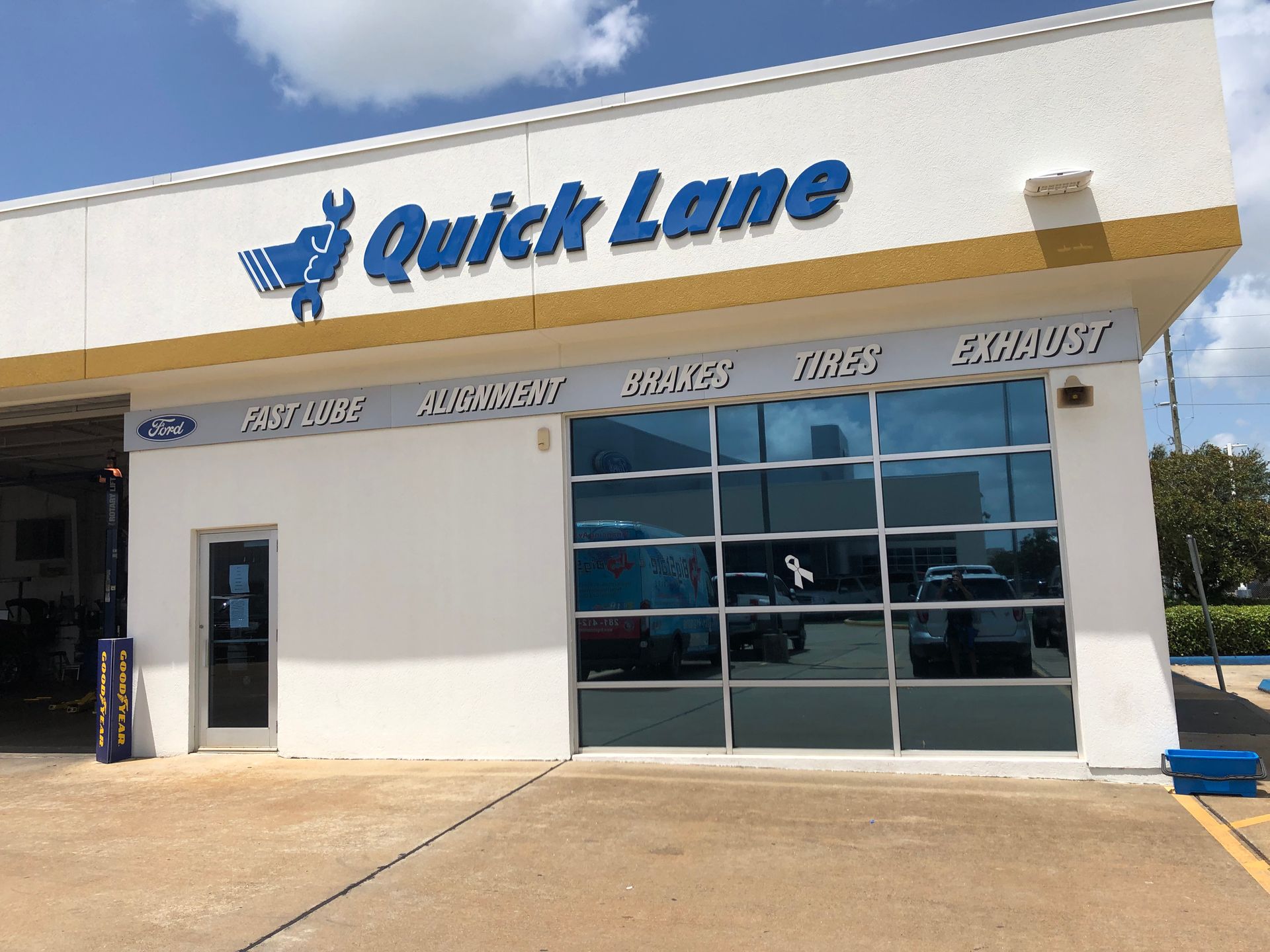 Quick Lane auto service center exterior with blue sign, glass doors, and white facade