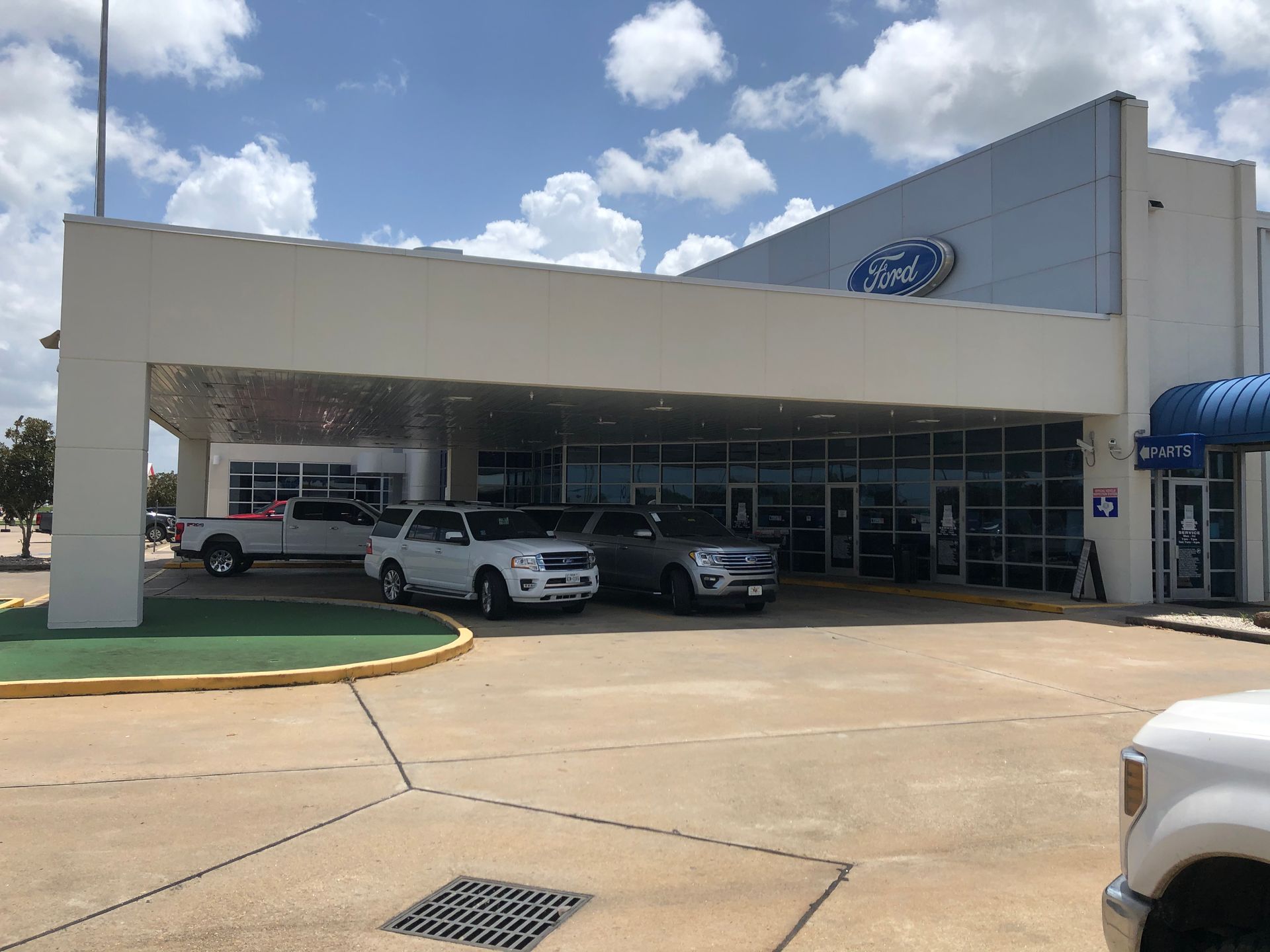 Ford dealership with parked cars under a canopy on a sunny day