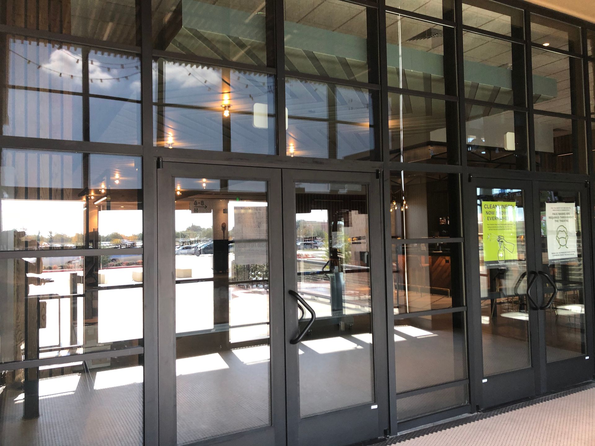 Glass entrance doors and windows reflecting a bright parking lot outside