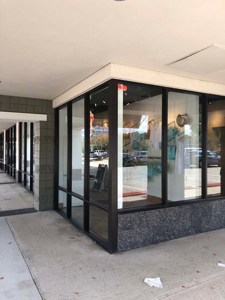 Storefront corner with large glass windows and black trim under a covered sidewalk.