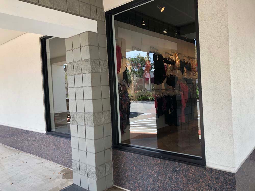 Storefront entrance with glass door, tiled column, and sidewalk reflection