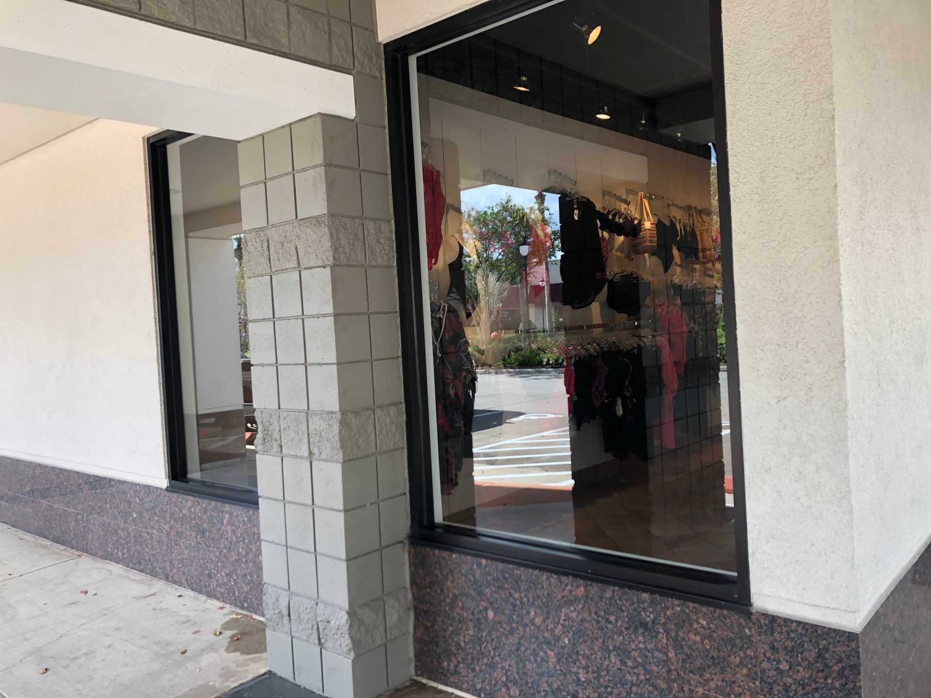 Storefront entrance with glass door and white tiled column under a covered walkway