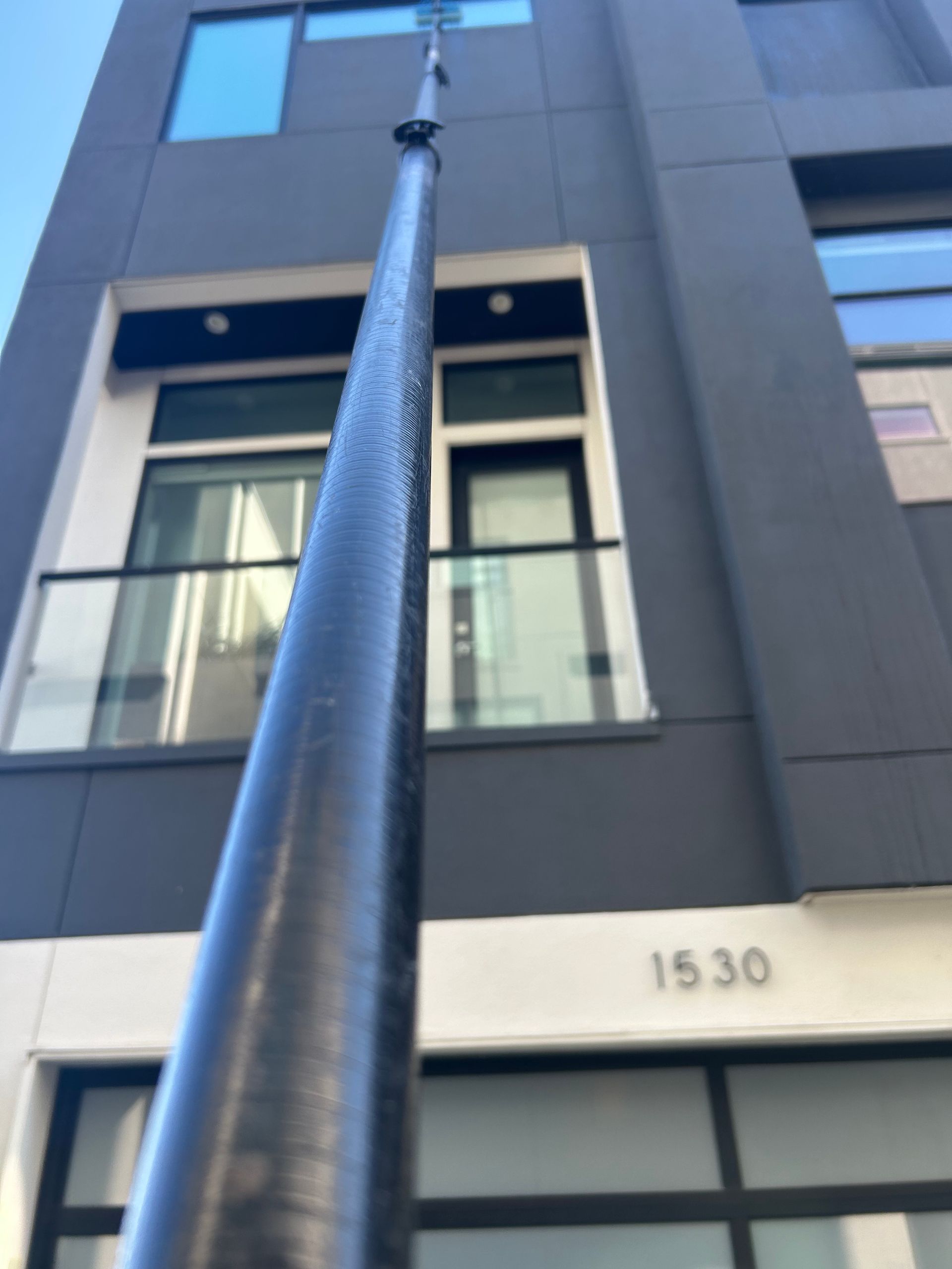 Low-angle view of a tall black streetlight in front of a gray building with the number 1530.