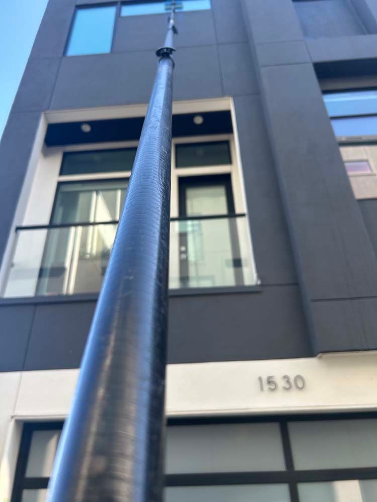 Tall black flagpole in front of a modern gray building with the number 1530 above the entrance.
