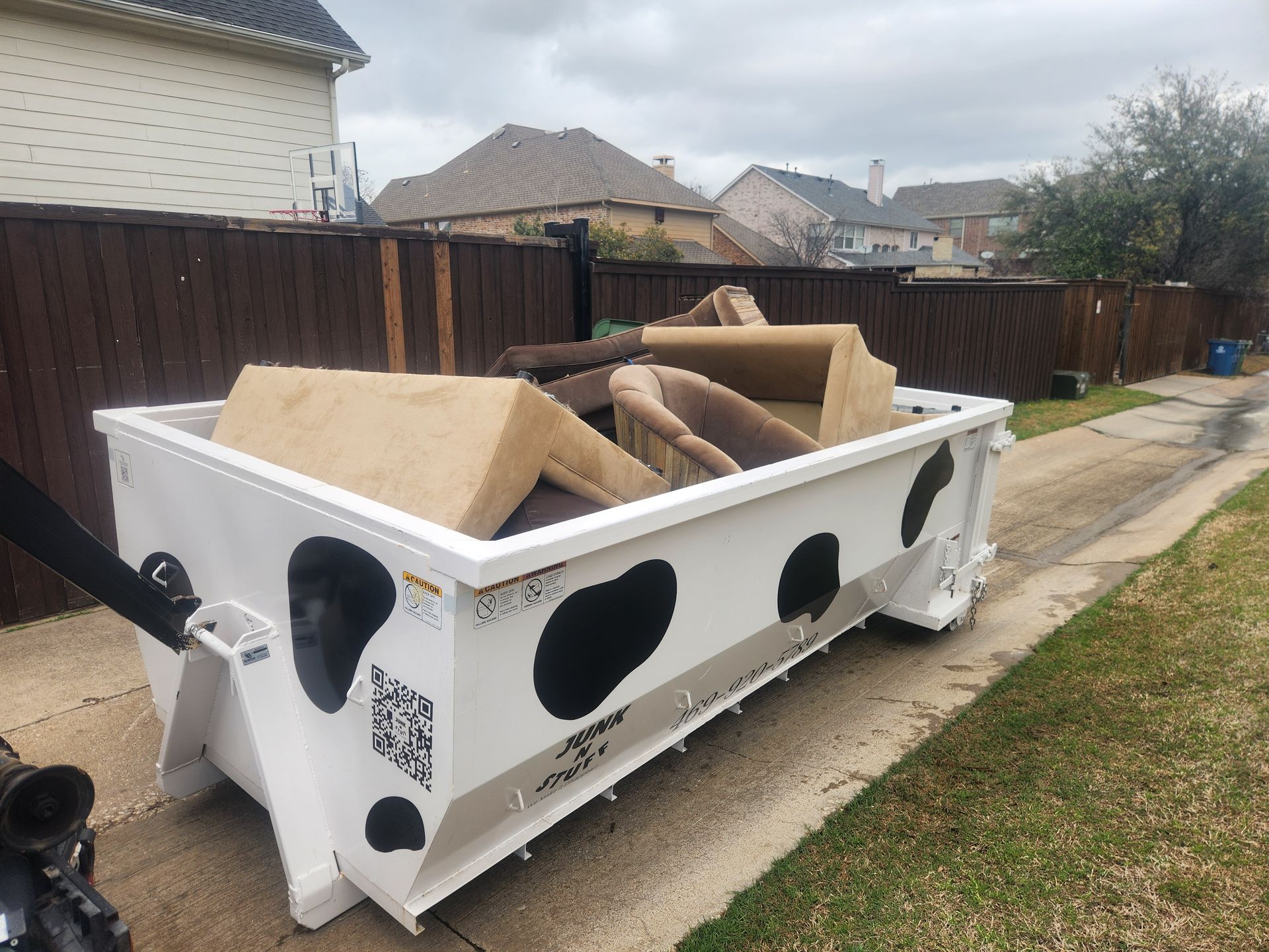 White construction dumpster filled with wood debris parked in a residential driveway