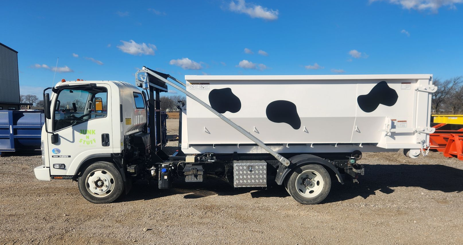 White utility trailer in a driveway in front of a garage, with a black front panel and hitch.