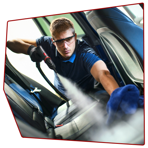 Person steam cleans car seat, wearing safety glasses and gloves, with a blue cloth in hand. Person steam cleans car seat, wearing safety glasses and gloves, with a blue cloth in hand.