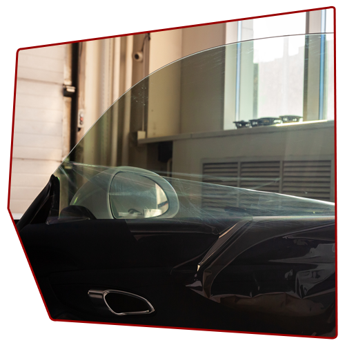 Car door window partially open, showing interior, side mirror, and building exterior visible. Car door window partially open, showing interior, side mirror, and building exterior visible.