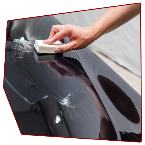 Hand waxing a black car panel with a white applicator. Hand waxing a black car panel with a white applicator.