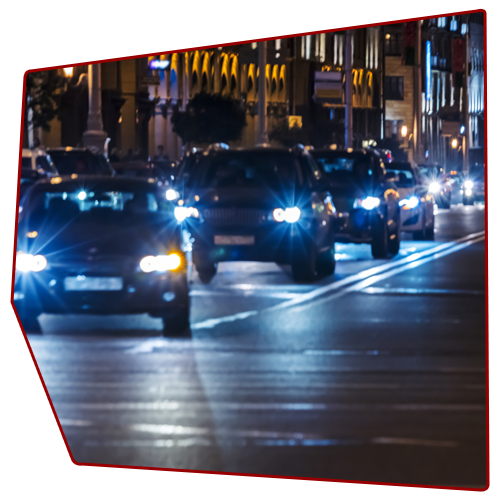 Cars driving on a city street at night, with bright headlights and city lights in the background. Cars driving on a city street at night, with bright headlights and city lights in the background.