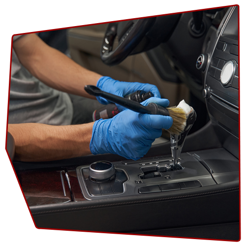 Person wearing blue gloves cleans a car's interior with a brush and cleaning solution. Person wearing blue gloves cleans a car's interior with a brush and cleaning solution.