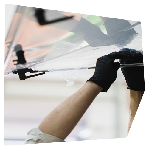 Person in black gloves assembling clear plastic sheets on a metal frame.